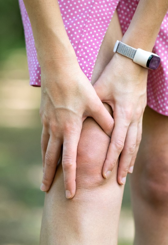 Woman holding her knee with hands having strong pain.